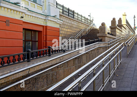 Omsk, Russia. Un grande e ripida rampa per sedia a rotelle accanto a una normale scala pedonale nella parte centrale della città. La combinazione del XIX secolo un Foto Stock