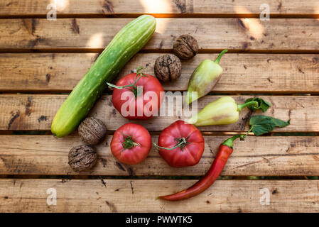 Verdure biologiche e noci da un piccolo giardino su una tavola in legno rustico - Pomodori, cetrioli, paprica, Peperone e peperoncino Foto Stock