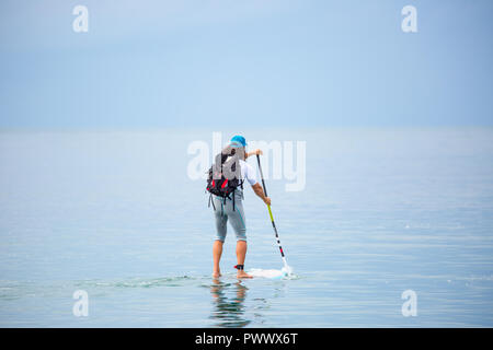 Maschio caucasico, vista posteriore, isolato in mare, godendo popolari attività outdoor, stand up paddle boarding (SUP surf) nel periodo delle vacanze estive, Wales UK. Foto Stock