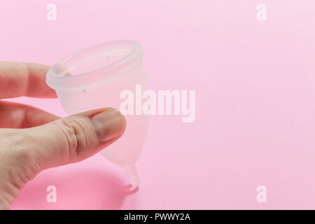 Stretta di mano donna azienda coppa mestruale su sfondo rosa. Salute della donna concetto, rifiuti zero alternative Foto Stock