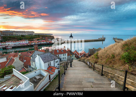 Tramonto mozzafiato oltre i 199 gradini che conducono giù al porto di Whitby sulla costa dello Yorkshire Foto Stock