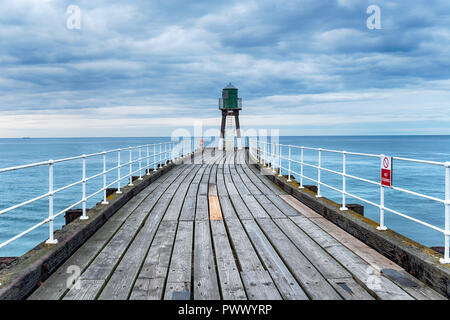 Moody cielo di Whitby pier sulla costa dello Yorkshire Foto Stock