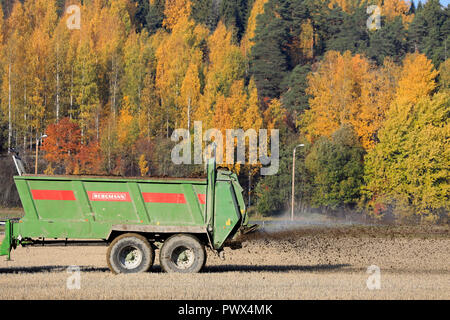 Salo, Finlandia - 14 Ottobre 2018: Bergmann spandiconcime trainato da un trattore a lavorare sul campo di stoppie su una bella giornata d'autunno. Foto Stock