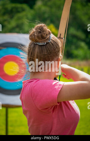 Un giovane femmina Archer mira il suo arco e frecce su un bersaglio Foto Stock