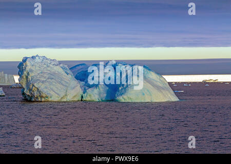 Iceberg galleggia sull'acqua aperto. È possibile vedere la parte subacquea di esso e il ghiaccio floes vicino ad essa. Antartico. Foto Stock