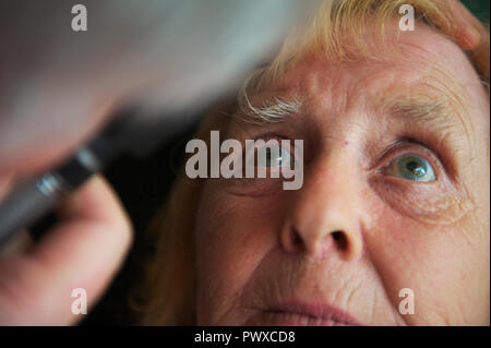 Anziani paziente femmina guarda i medici o GP visita oculistica luce durante l'Appuntamento al GP di chirurgia o visita della comunità Foto Stock