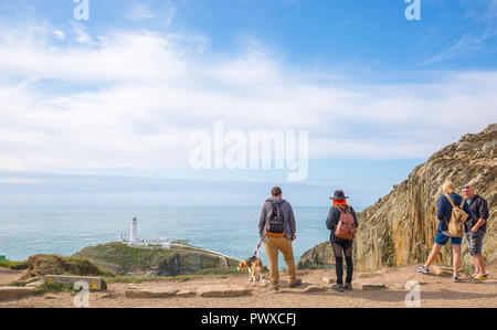Vista posteriore del popolo stava in piedi al sole (A RSPB Sud pila scogliere) fissando il paesaggio: guardando fuori in mare a sud del faro di stack, Anglesey, Regno Unito. Foto Stock