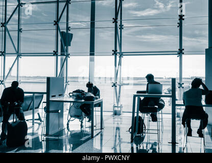 Persone che utilizzano dispositivi mobili e computer portatili in zona Wifi all'aeroporto El Prat di Barcellona. Spagna Foto Stock