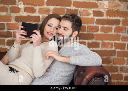 Felice coppia giovane la navigazione online su tablet a casa natale dello shopping online Foto Stock