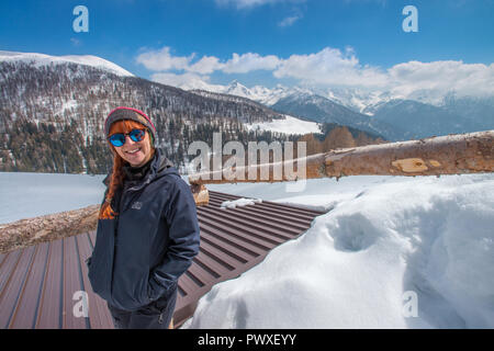 Felice escursionista in un Helly Hansen giacca sorridente dietro i suoi occhiali da sole. Viaggiatore godendo una giornata di escursioni con le racchette da neve sulla neve. Di polvere fresca di montagna. Foto Stock