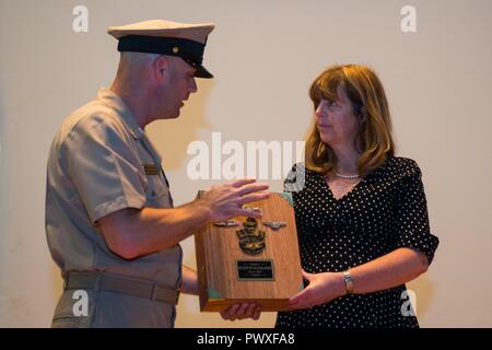 NORFOLK (Luglio 6, 2017) Senior Chief la comunicazione di massa Specialist Jim Perkins, assegnato al navale attività di supporto est, presenta Katherine "Kathy" McRill-Fellini, vedova di Robert "Bobby" McRill, una carica simbolo Libro dall'Hampton Roads Area Chief's pasticcio durante una cerimonia in cui McRill è stato promosso a Capo onorario Petty Officer. McRill fu ucciso in azione durante l'Operazione Iraqi Freedom il 6 Luglio 2007 da na improvvisato dispositivo esplosivo. Foto Stock