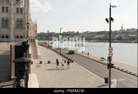 Budapest, Ungheria - 4 August 2018: vista del fiume Danubio, di fronte al palazzo del parlamento con le automobili e la gente a piedi Foto Stock