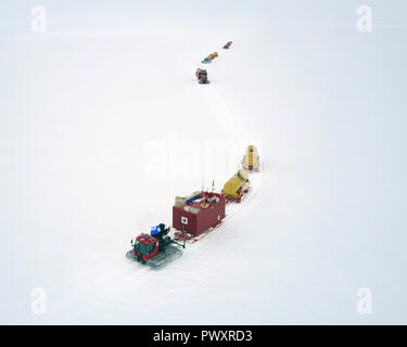 Un gruppo di motoslitte è camminare lungo la pianura innevate. Convoglio di neve. Antartico. Vista da sopra. Foto Stock