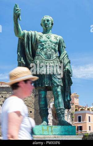 Una passeggiate turistiche passato una statua in bronzo di imperatore romano Giulio Cesare accanto al Forum di agosto a Roma, lazio, Italy Foto Stock
