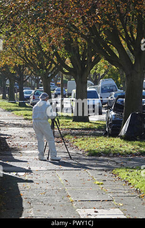 Liverpool, Regno Unito. Il 18 ottobre 2018. Un cordone di polizia attorno ad un bruciato auto in strada Abbeystead Childwall. Un colore scuro Audi abbandonate su un orlo di erba, 1.7 miglia da ultima notte di riprese in Alderson Rd, Wavertree. Un forensics officer è di scattare foto e la raccolta delle prove sulla scena. La polizia non sono dicendo in questa fase se la vettura è stata coinvolta in ultima notte di omicidio. Credito: Ken Biggs/Alamy Live News. Foto Stock