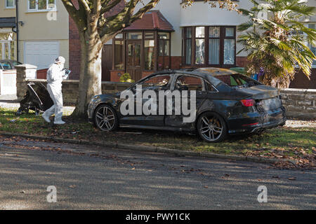 Liverpool, Regno Unito. Il 18 ottobre 2018. Un cordone di polizia attorno ad un bruciato auto in strada Abbeystead Childwall. Un colore scuro Audi abbandonate su un orlo di erba, 1.7 miglia da ultima notte di riprese in Alderson Rd, Wavertree. Un forensics officer è di scattare foto e la raccolta delle prove sulla scena. La polizia non sono dicendo in questa fase se la vettura è stata coinvolta in ultima notte di omicidio. Credito: Ken Biggs/Alamy Live News. Foto Stock