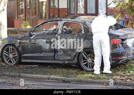 Liverpool, Regno Unito. Il 18 ottobre 2018. Un cordone di polizia attorno ad un bruciato auto in strada Abbeystead Childwall. Un colore scuro Audi abbandonate su un orlo di erba, 1.7 miglia da ultima notte di riprese in Alderson Rd, Wavertree. Un forensics officer è di scattare foto e la raccolta delle prove sulla scena. La polizia non sono dicendo in questa fase se la vettura è stata coinvolta in ultima notte di omicidio. Credito: Ken Biggs/Alamy Live News. Foto Stock