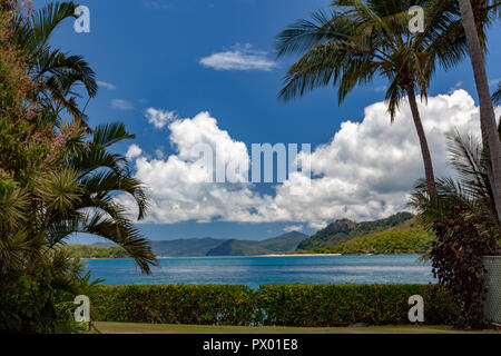I cieli blu, soffici nuvole, palme, aqua, azzurro, giallo e verde bottiglia, acque di lappatura della white coral sands della Grande Barriera Corallina Foto Stock