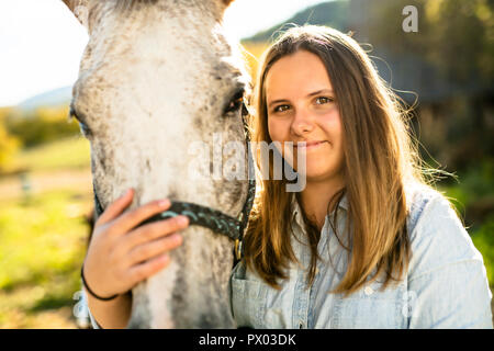 Una bella ragazza teen in agriturismo con il suo cavallo. Foto Stock