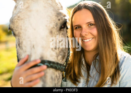 Una bella ragazza teen in agriturismo con il suo cavallo. Foto Stock