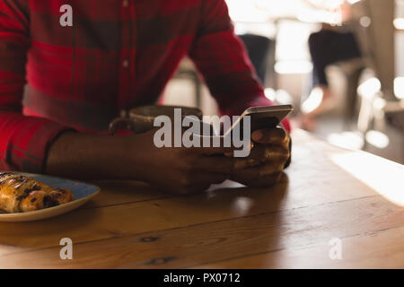 Uomo che utilizza un cellulare in cafe Foto Stock