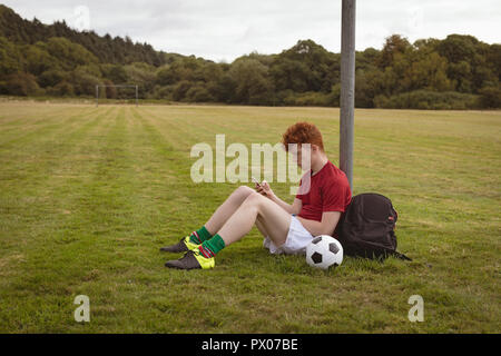 Football player utilizzando il telefono cellulare nel campo Foto Stock