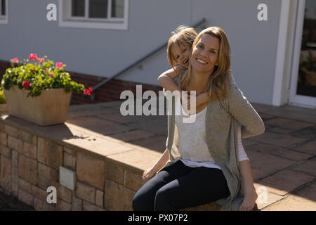 Madre dando piggyback ride a sua figlia nel portico Foto Stock