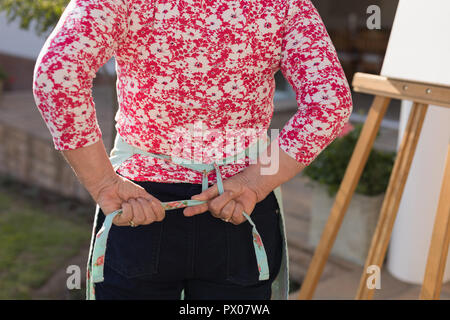 Senior donna che indossa il grembiule in giardino Foto Stock