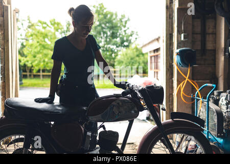 Meccanico femmina in piedi vicino a moto Foto Stock