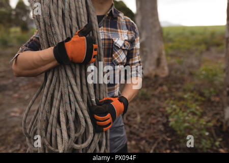 Lumberjack tenendo la corda in foresta Foto Stock