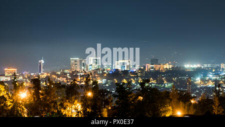 Una vista panoramica di Kigali skyline della città illuminata di notte, al di sotto di un profondo blu del cielo della sera con il bagliore dei lampioni Foto Stock