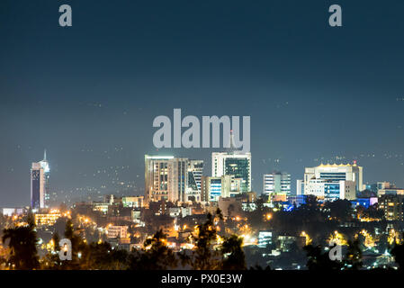 Un primo piano di Kigali skyline della città illuminata di notte, al di sotto di un profondo blu del cielo della sera Foto Stock