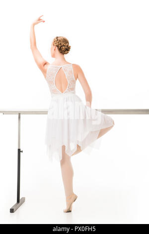 Vista posteriore della ballerina in tutù e pointe scarpe pratica presso ballet barre stand isolato su sfondo bianco Foto Stock