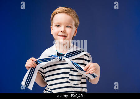 Adorable boy in costume da marinaio con striped t-shirt, isolato su blu Foto Stock