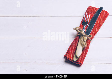 Vacanza di Natale sfondo alimentare concetto. Tavola di natale con un set di posate coltello e forchetta su un tovagliolo rosso con decorazioni di Natale. Legno bianco indietro Foto Stock