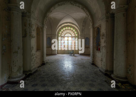 Vista interna con una sedia a rotelle all'ingresso di un ospedale abbandonato in Italia. Foto Stock
