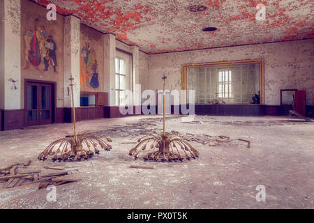 Vista interna di un abbandonato la sala da ballo con peeling di vernice sul soffitto e lampadari sul pavimento in Germania. Foto Stock