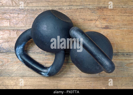 Due pesanti kettlebell nero su sfondo di legno Foto Stock