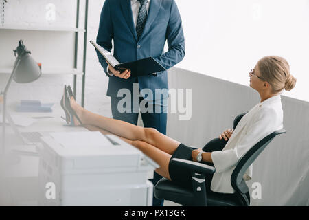 Imprenditore con documenti e collega incinta discutendo il lavoro al lavoro in ufficio Foto Stock