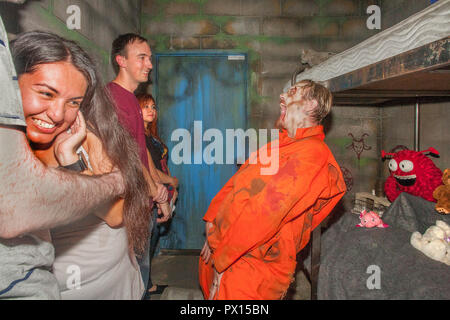 Al diciassettesimo porta Halloween Haunted House in Fullerton, CA, il detenuto del 'Dark cell" ride follemente come un visitatore cringes. Foto Stock