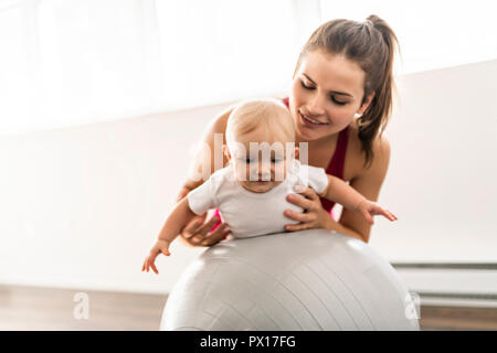 Un Ritratto di giovane e bella madre di indossare abbigliamento sportivo con il suo affascinante piccolo bambino nella sessione di formazione Foto Stock