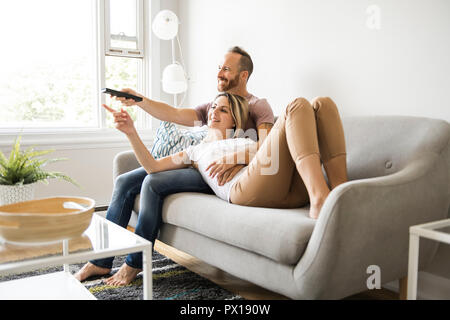 Paio di guardare la tv a casa seduti in un comodo divano in soggiorno a casa Foto Stock