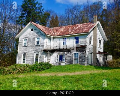 Vecchia fattoria abbandonata casa, bianco con rosso tetto arrugginito, nelle zone rurali del nord della Pennsylvania centrale, Sullivan County, Stati Uniti d'America. Foto Stock