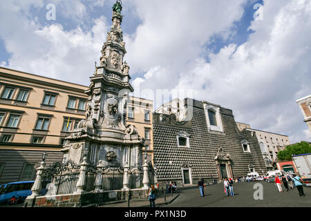 La Guglia o Guglia dell'Immacolata Vergine e la Chiesa del Gesu Nuovoin a Napoli, Italia meridionale. La Chiesa del Gesu Nuovo era originariamente un palazzo costruito nel 1470 per Roberto Sanseverino, principe di Salerno. Il singolare edificio si trova ad affrontare con bugnato rustico proiezioni di diamante. Foto Stock