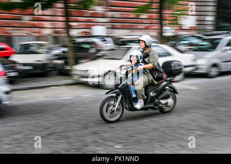 Uno scooter a motore con la madre e il bambino ride giù per una strada a Napoli, Italia meridionale. Foto Stock