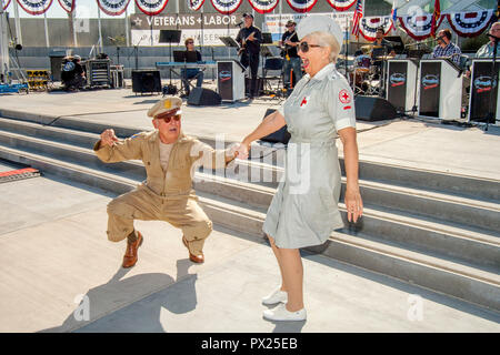 Una guerra mondiale II veterano nel US Army uniforme e una donna vestita come un volontario della Croce Rossa felicemente la danza jutterbug a veterani Day celebrazione in Costa Mesa, CA. Foto Stock