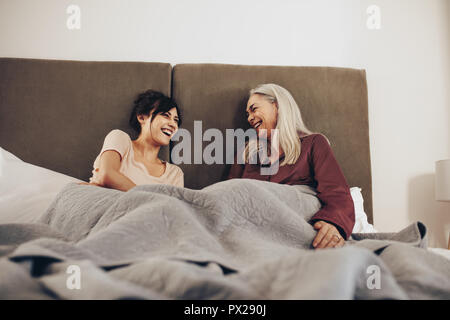 Donna anziana seduta sul letto con sua figlia e ridere. Madre e figlia di trascorrere del tempo insieme a casa. Foto Stock