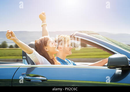 Coppia giovane indossando occhiali da sole che viaggiano in auto Foto Stock