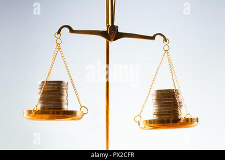Close-up di Golden monete impilate su scala di giustizia Foto Stock