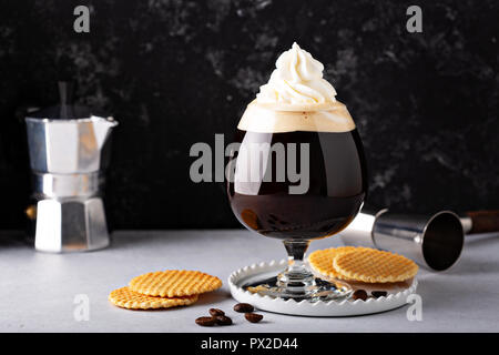 Irish coffee in un bicchiere da cocktail con panna montata Foto Stock